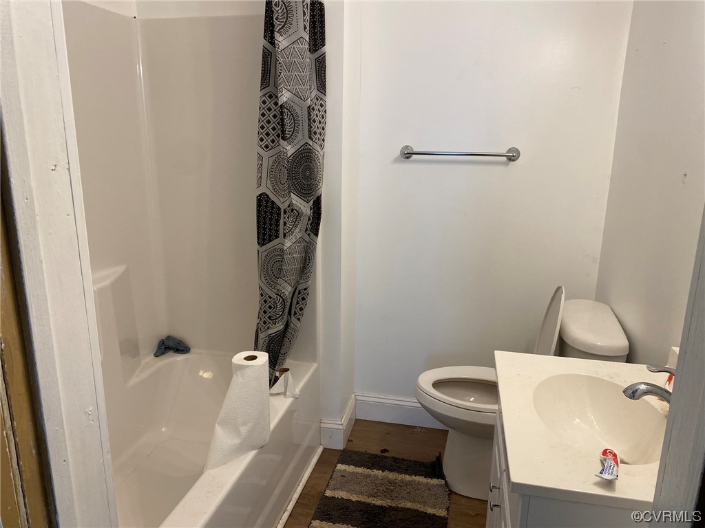 Full bathroom with shower / bath combo, toilet, hardwood / wood-style floors, and sink