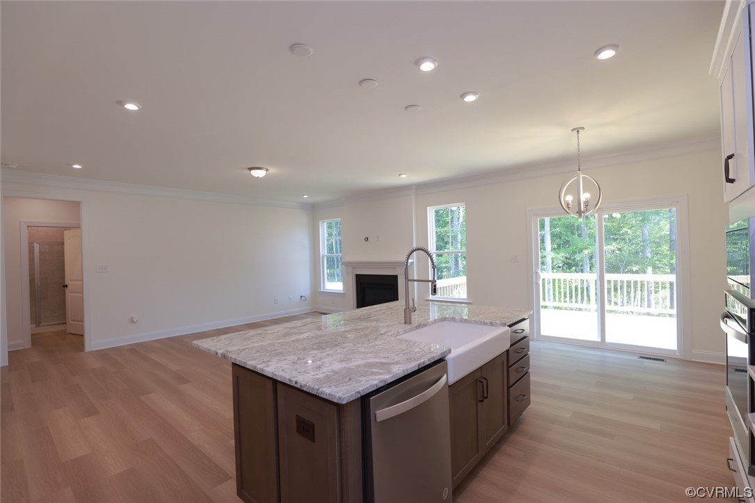 Large, inviting kitchen is open to the family room w/ gas fireplace &  features granite counters, wall oven/microwave, gas cooking, stainless steel range hood, large island w/ barstool area & pantry.