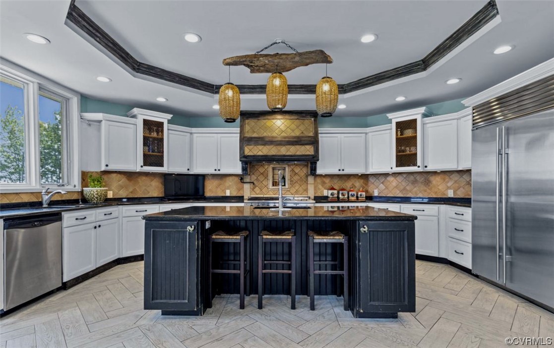 Kitchen featuring a kitchen island with sink, light parquet flooring, stainless steel appliances, and backsplash
