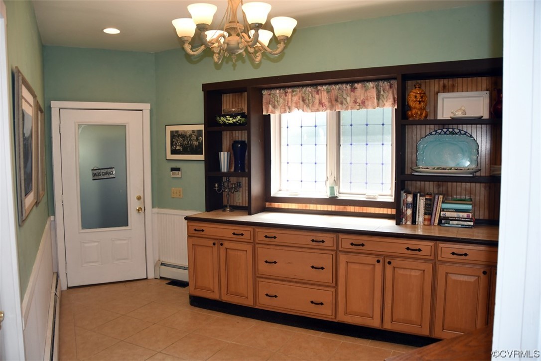 Kitchen featuring a baseboard heating unit, light tile floors, and a notable chandelier
