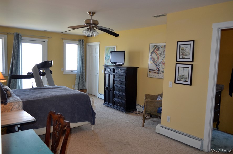 Bedroom featuring light carpet, a baseboard heating unit, and ceiling fan