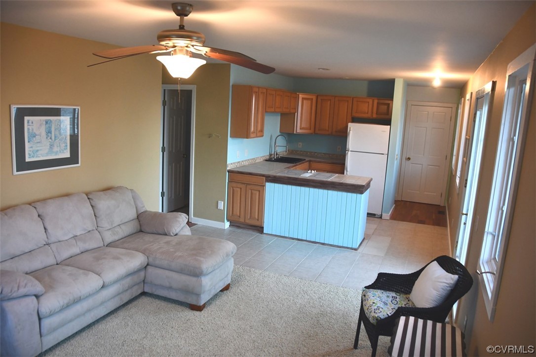 Living room featuring sink, ceiling fan, and light colored carpet