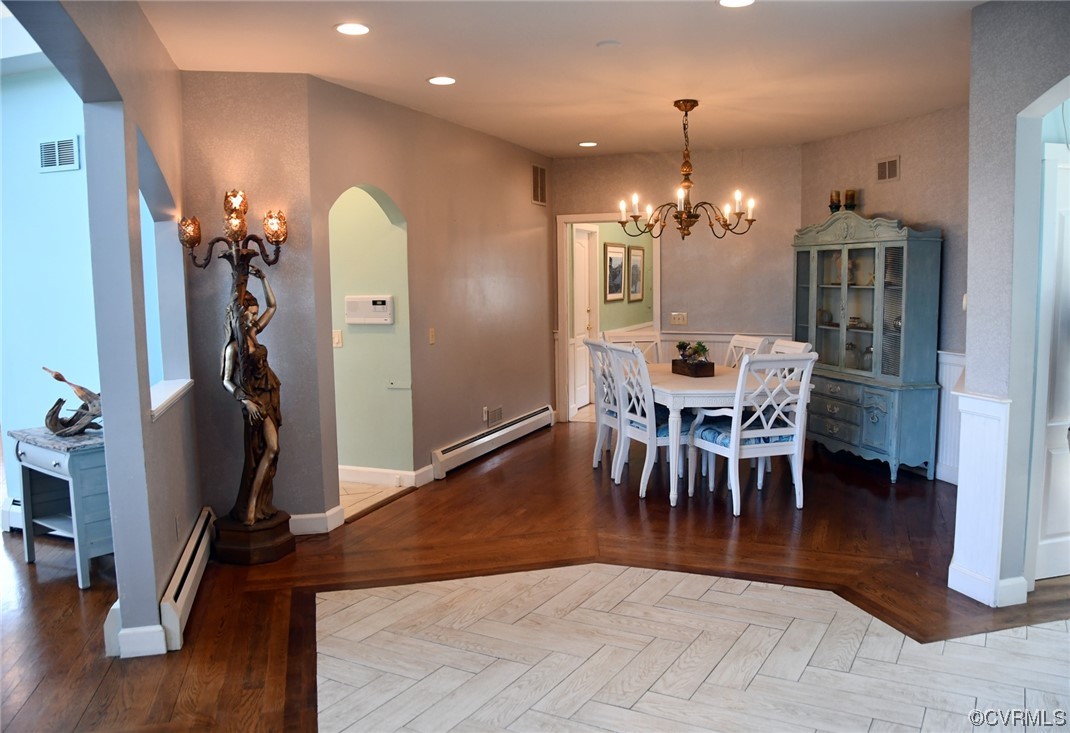 Dining space with a notable chandelier, dark parquet floors, and baseboard heating