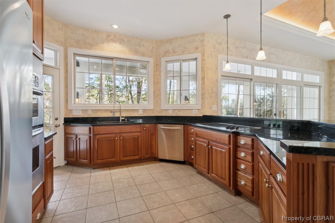 Kitchen featuring light tile flooring, sink, hanging light fixtures, and stainless steel appliances