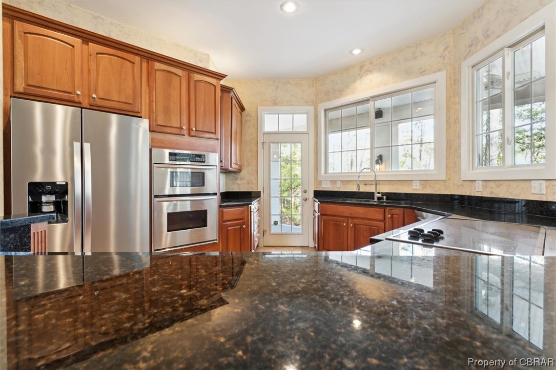 Kitchen featuring sink, appliances with stainless steel finishes, and dark stone countertops