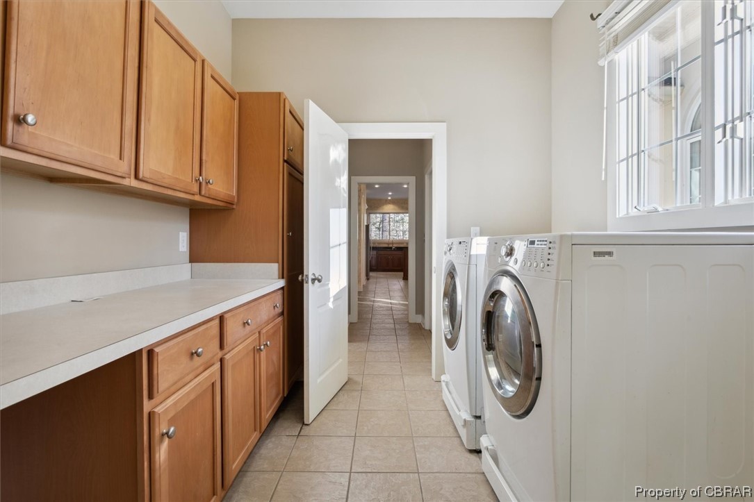 Washroom with a wealth of natural light, cabinets, separate washer and dryer, and light tile floors
