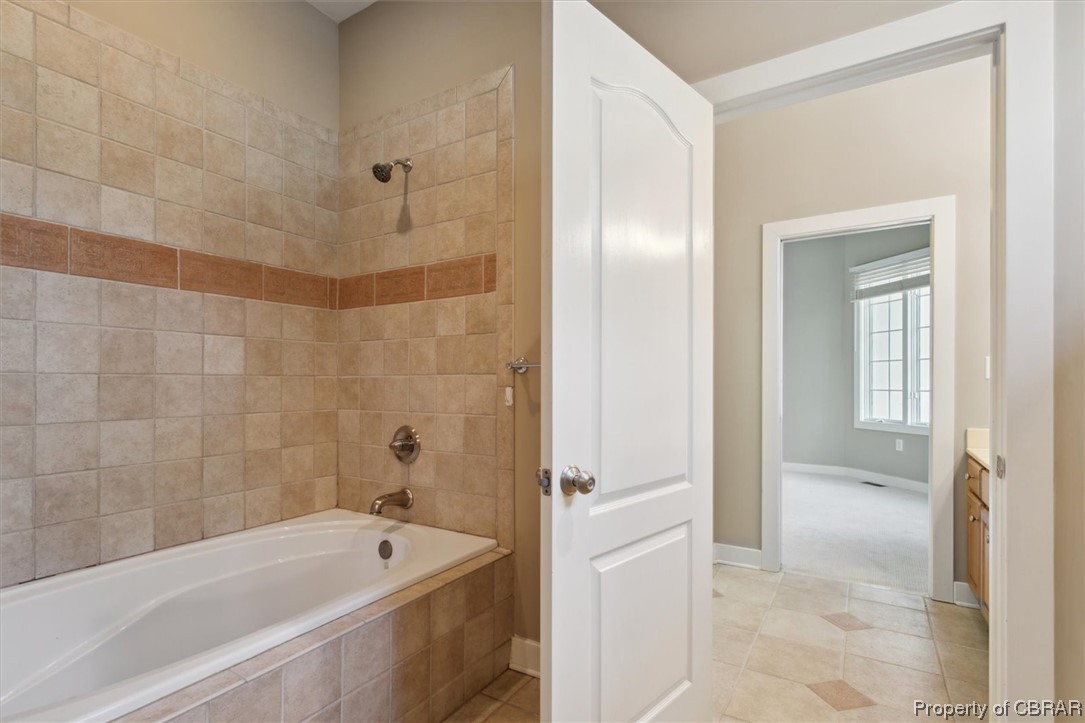 Bathroom with tile floors, tiled shower / bath, and vanity