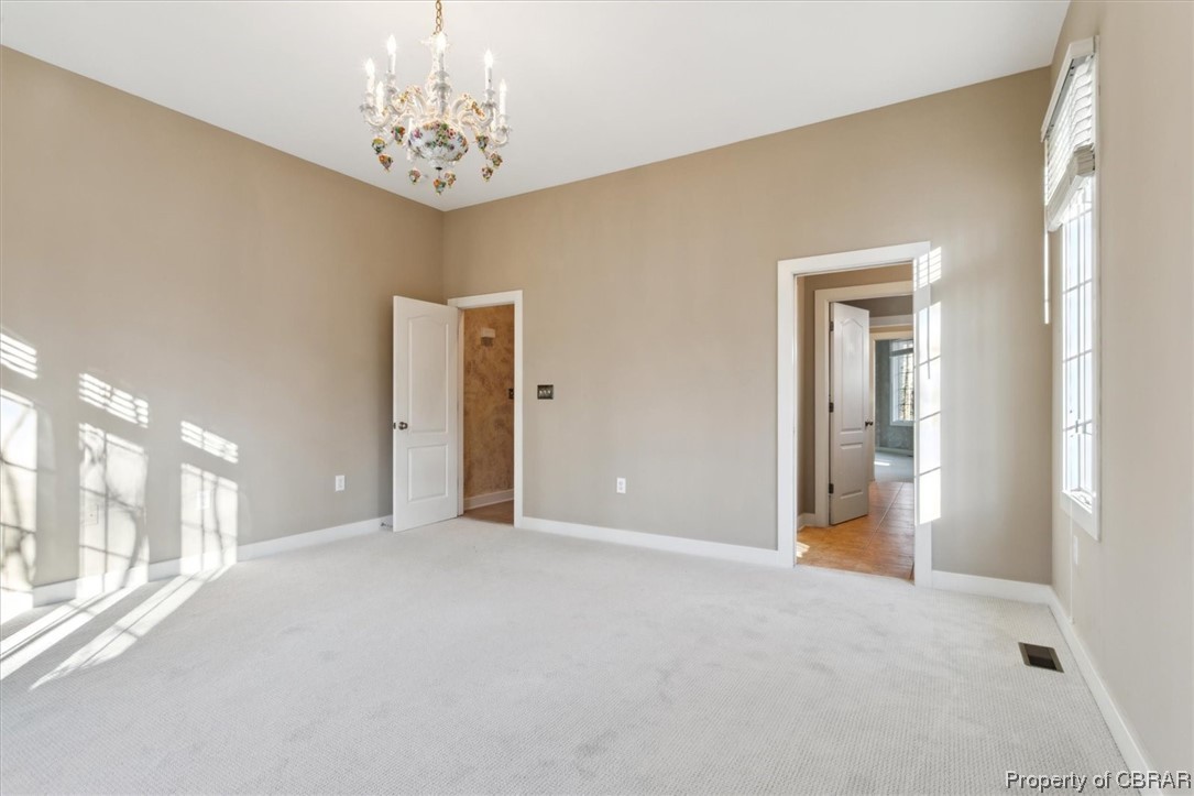 Unfurnished room with a chandelier and light carpet