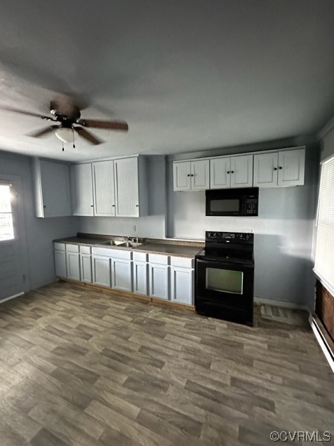 Kitchen featuring sink, baseboard heating, range, dark hardwood / wood-style floors, and ceiling fan