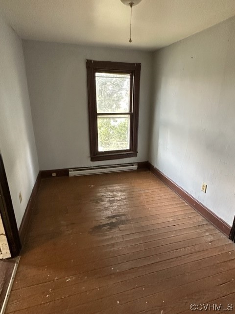 Spare room with dark hardwood / wood-style floors and a baseboard heating unit