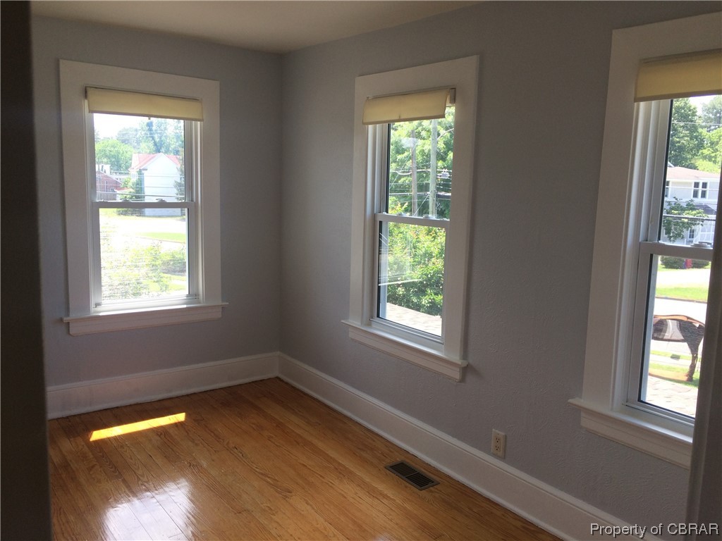 Spare room with a wealth of natural light and hardwood / wood-style flooring