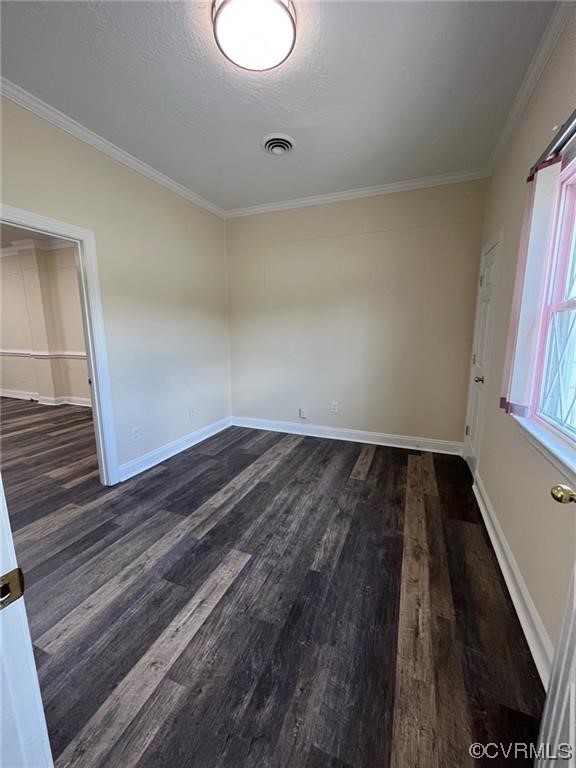 Spare room with crown molding and dark wood-type flooring