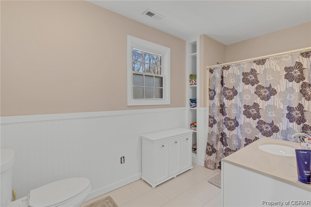 Full bathroom with shower / tub combo with curtain, toilet, vanity, and tile floors