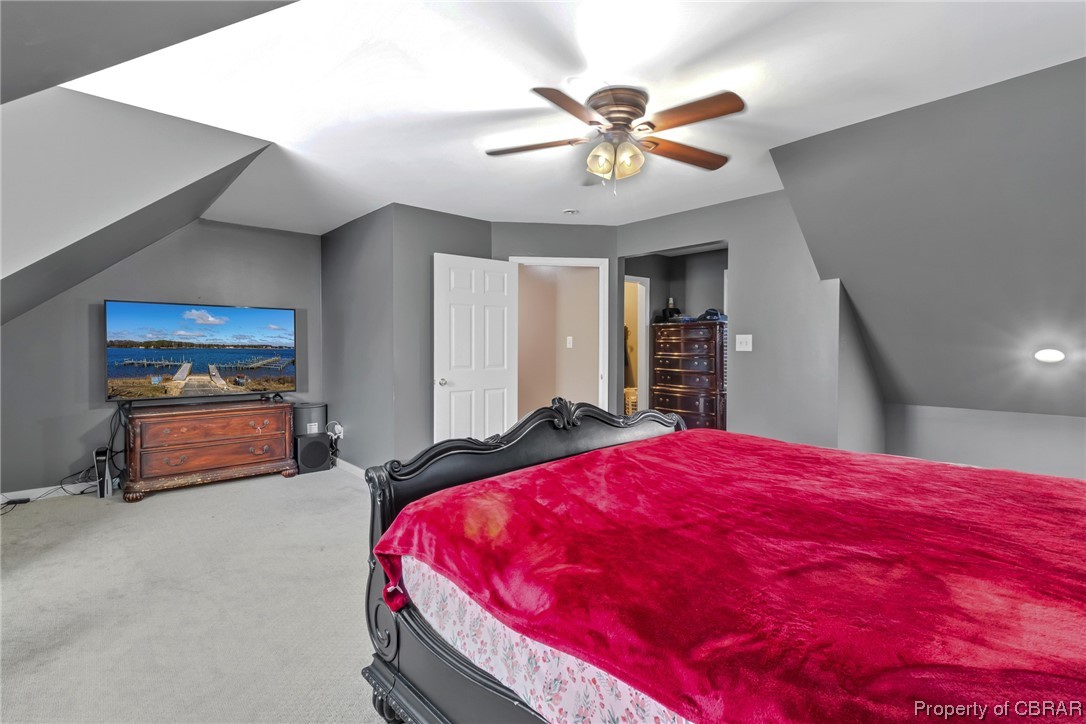 Bedroom featuring vaulted ceiling, carpet flooring, and ceiling fan
