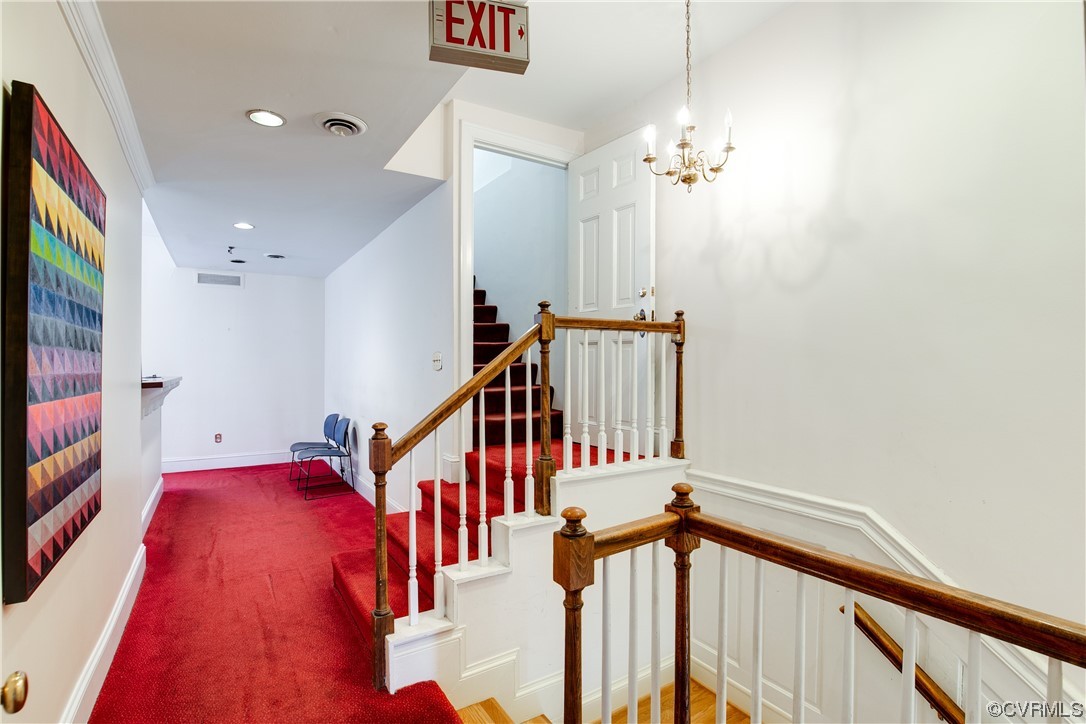 Stairway featuring ornamental molding, a chandelier, and carpet