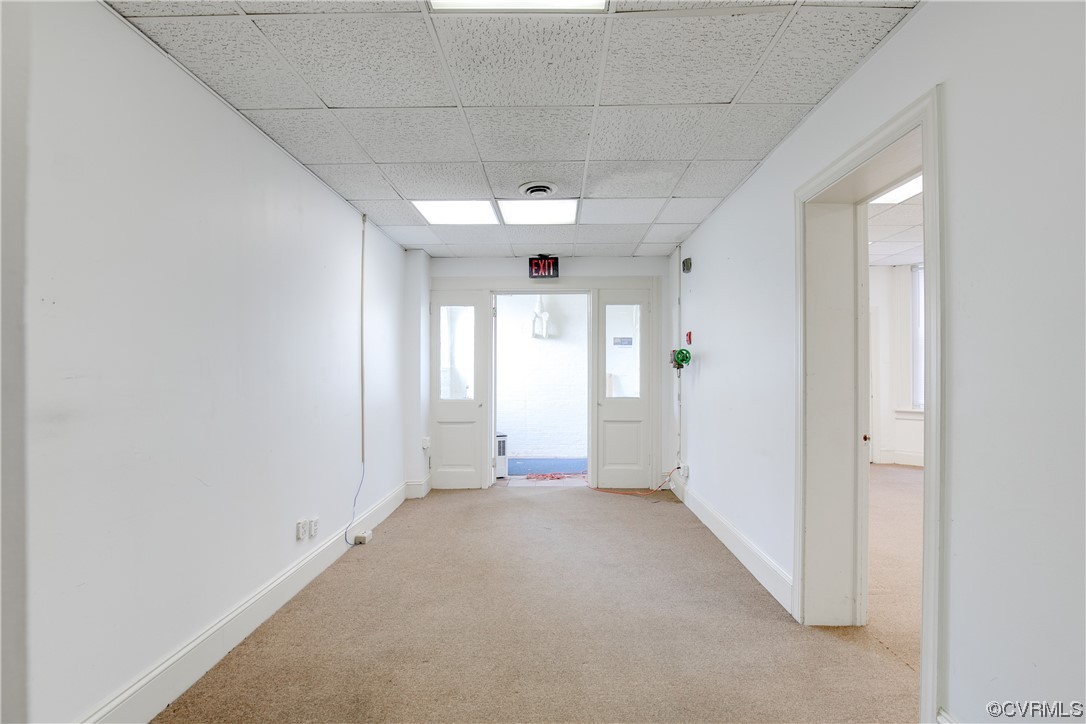 Corridor with a drop ceiling and light colored carpet