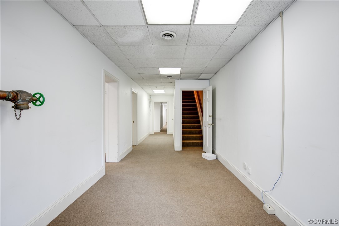 Hallway featuring a drop ceiling and light colored carpet