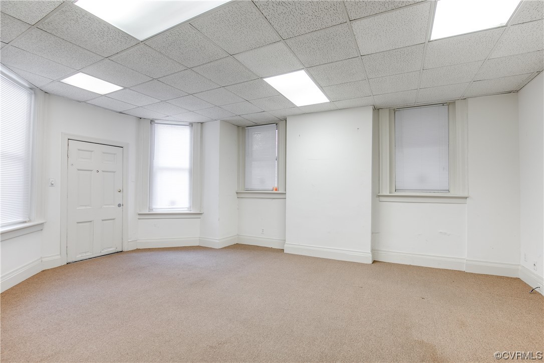 Empty room featuring light colored carpet and a paneled ceiling