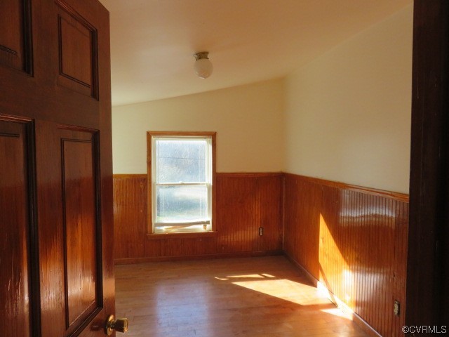 Spare room with lofted ceiling and hardwood / wood-style flooring
