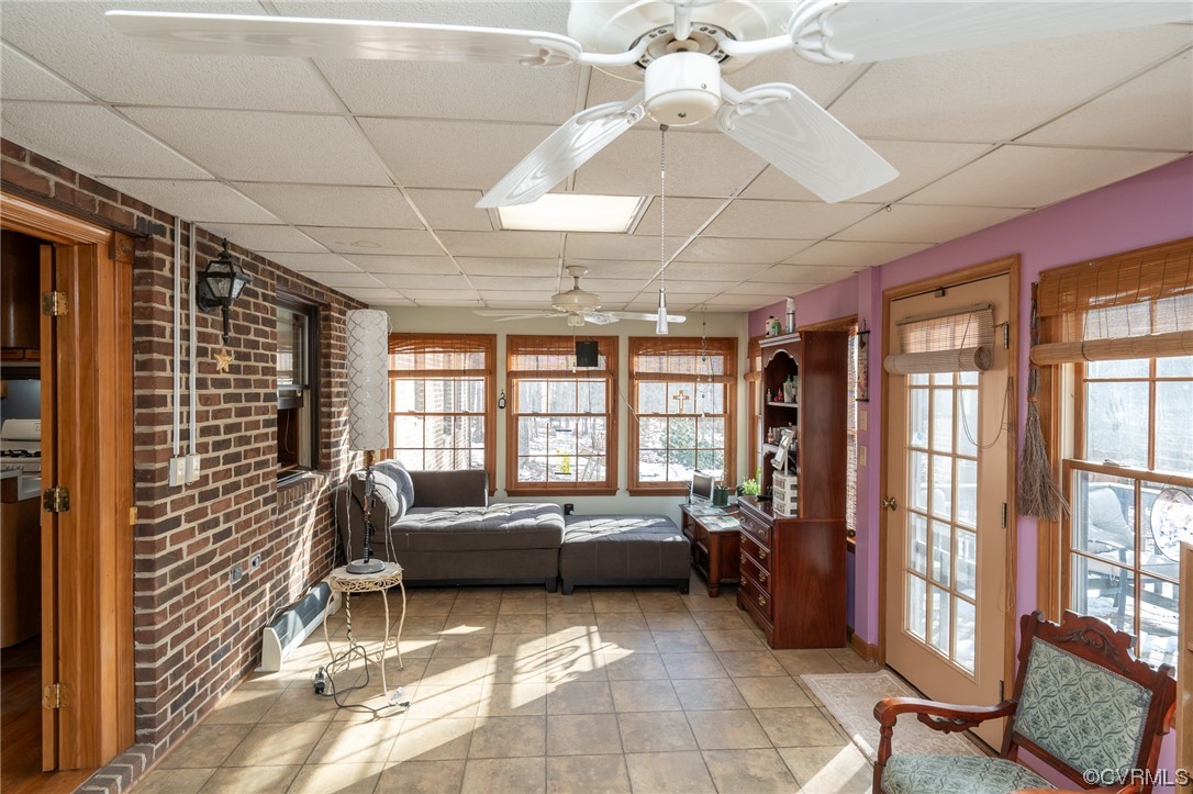 Unfurnished sunroom featuring plenty of natural light, a paneled ceiling, and ceiling fan