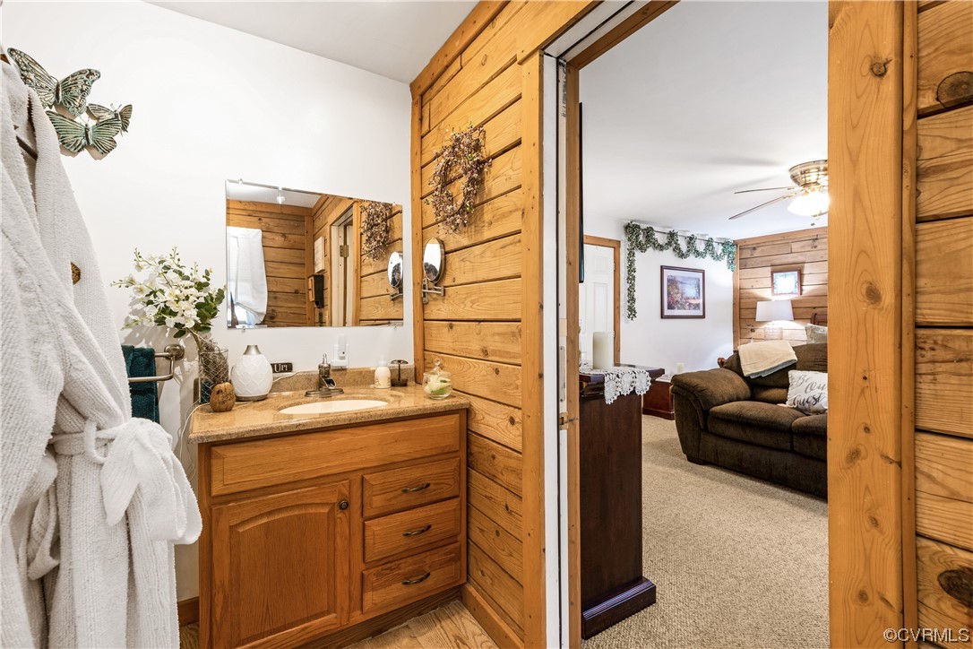 Bathroom featuring wooden walls, vanity, and ceiling fan