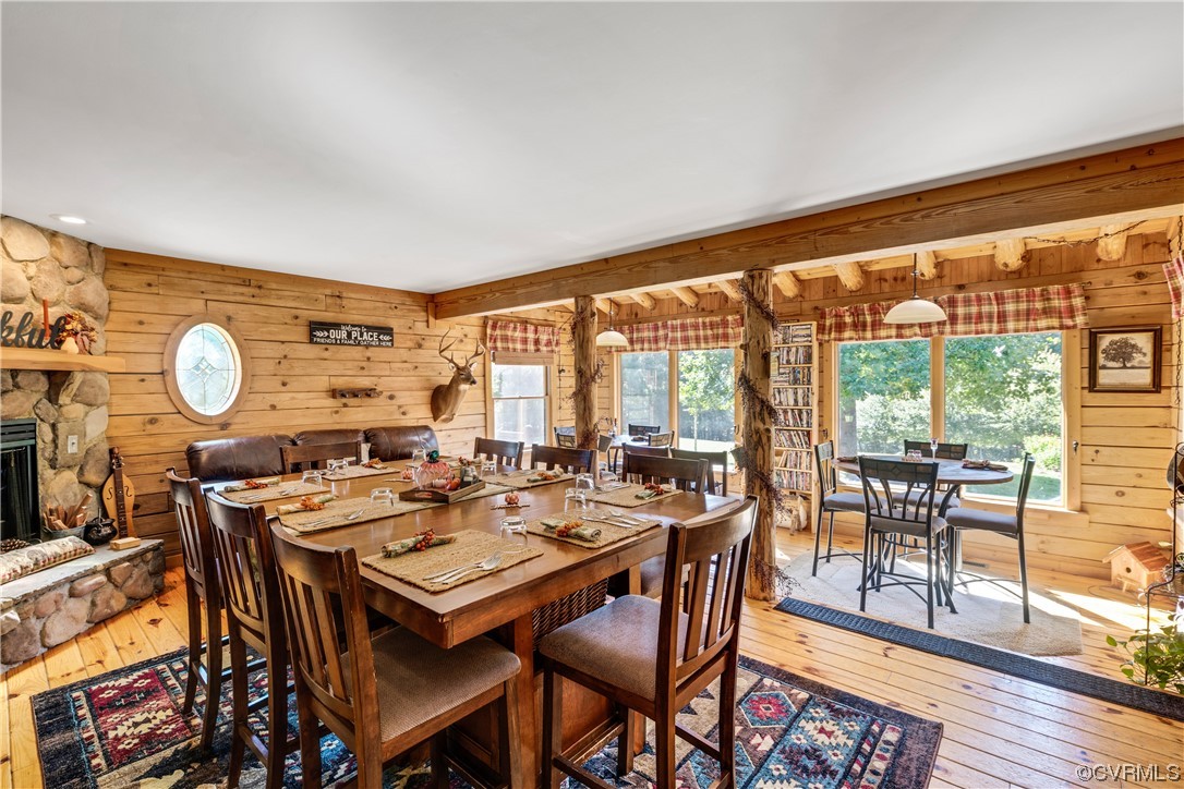 Dining room featuring light hardwood / wood-style floors, wooden walls, and a fireplace
