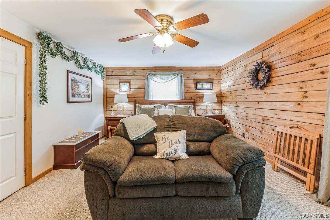 Carpeted living room featuring wood walls and ceiling fan