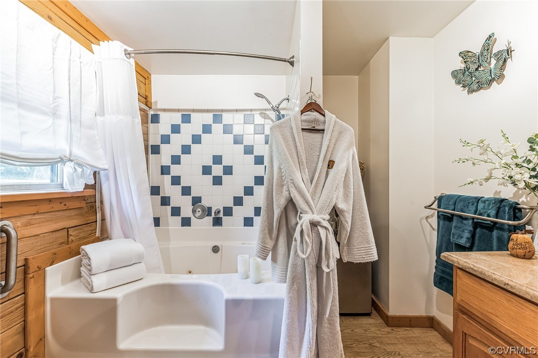 Bathroom with hardwood / wood-style flooring and shower / bath combo