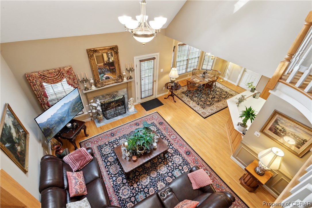 Living room with hardwood / wood-style floors, a notable chandelier, and high vaulted ceiling