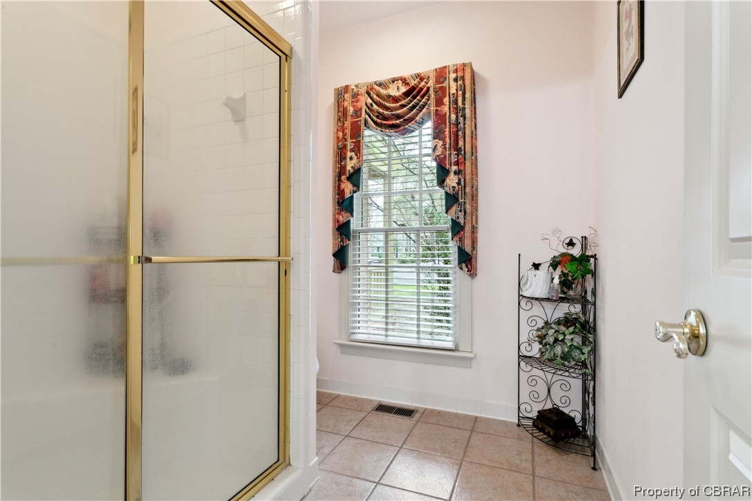 Bathroom with an enclosed shower and tile flooring