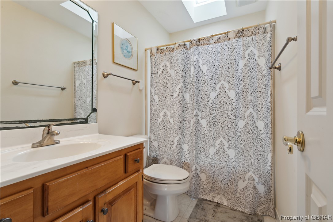 Bathroom with large vanity, a skylight, tile floors, and toilet