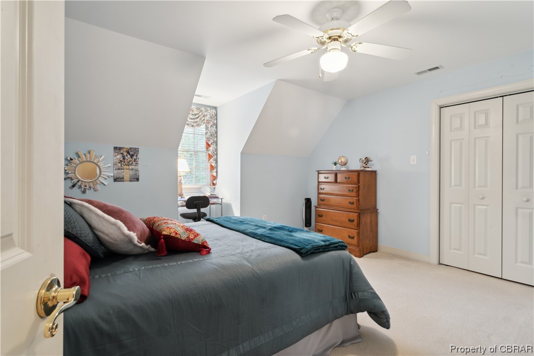 Bedroom featuring ceiling fan, light colored carpet, vaulted ceiling, and a closet