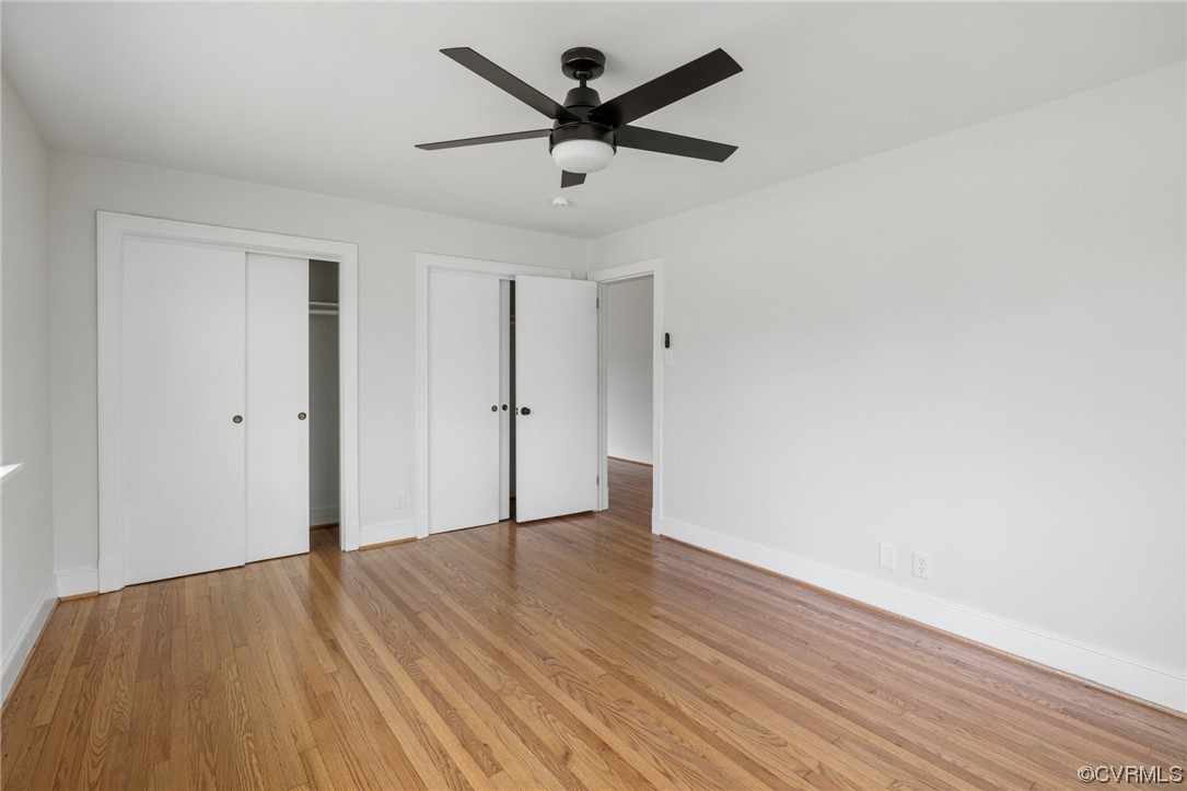 Unfurnished bedroom with multiple closets, light hardwood / wood-style flooring, and ceiling fan