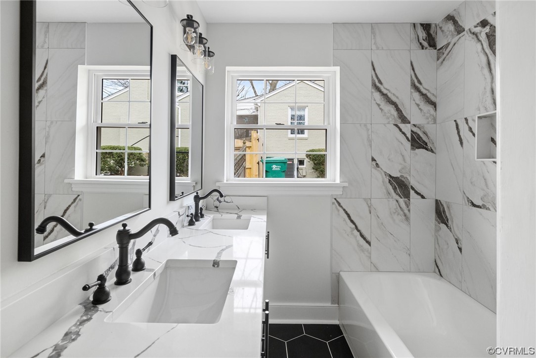 Bathroom featuring a tub, dual sinks, tile floors, and oversized vanity