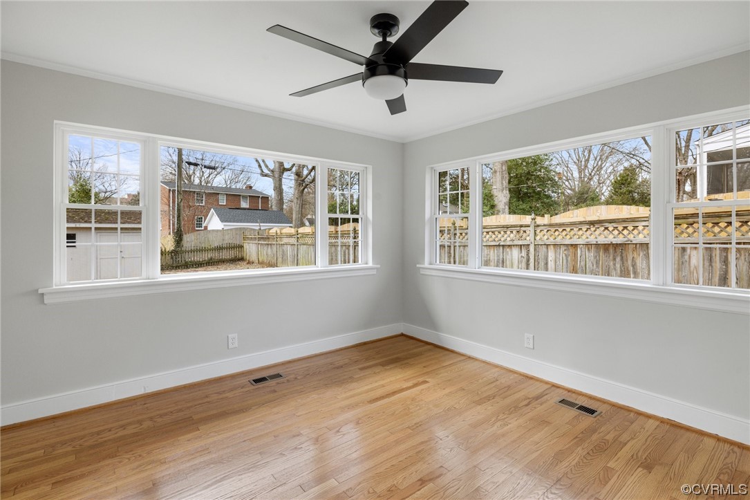 Spare room with a wealth of natural light, ceiling fan, and light hardwood / wood-style flooring