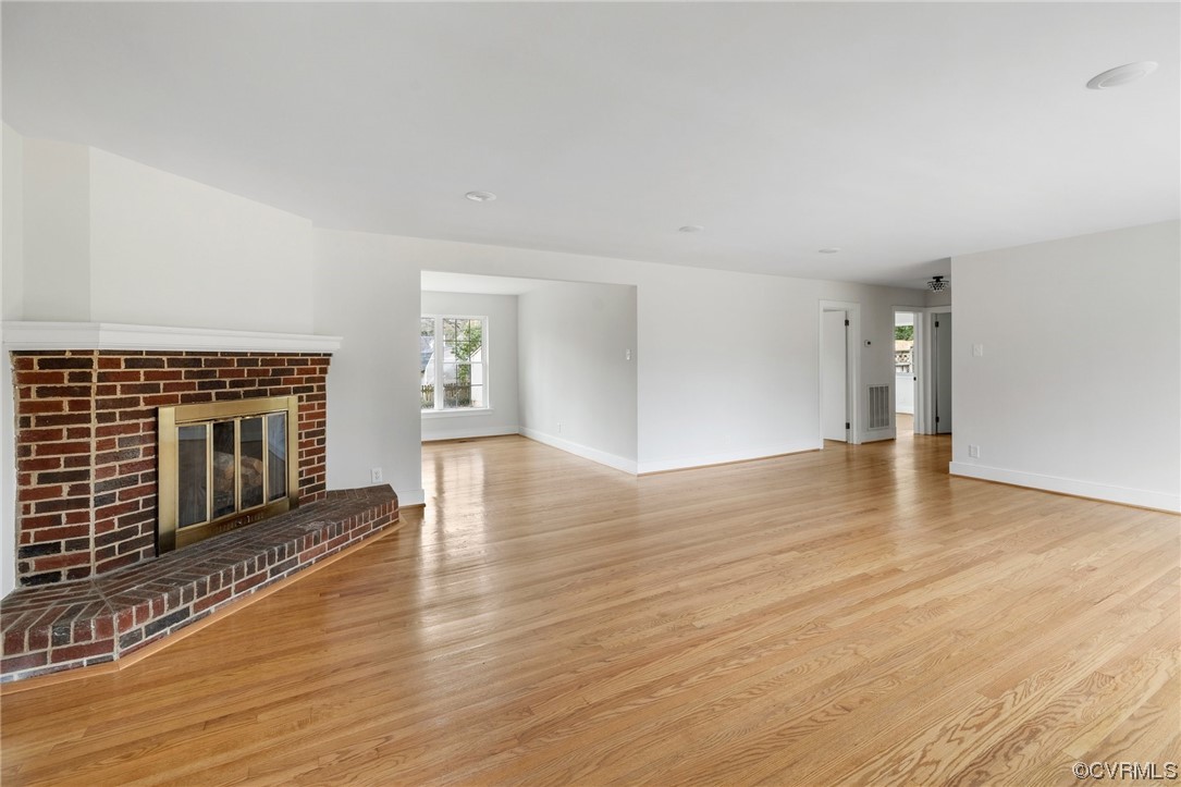 Unfurnished living room featuring light hardwood / wood-style floors and a brick fireplace