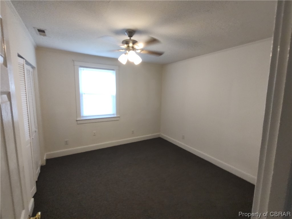 Spare room with new carpet, ceiling fan, and a textured ceiling
