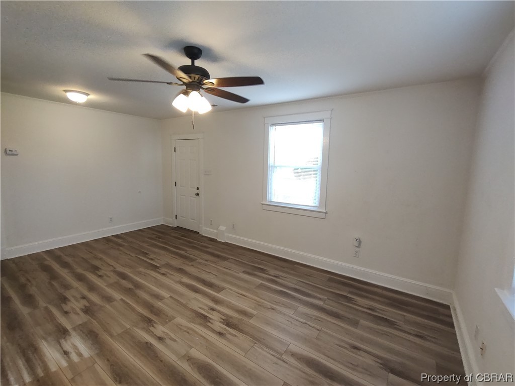 Empty room with laminate / wood-style flooring and ceiling fan