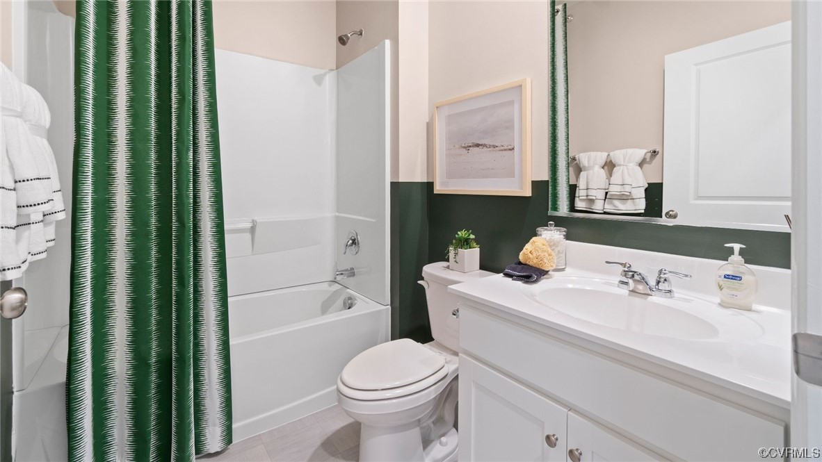 Full bathroom featuring shower / bath combo, toilet, vanity, and tile flooring