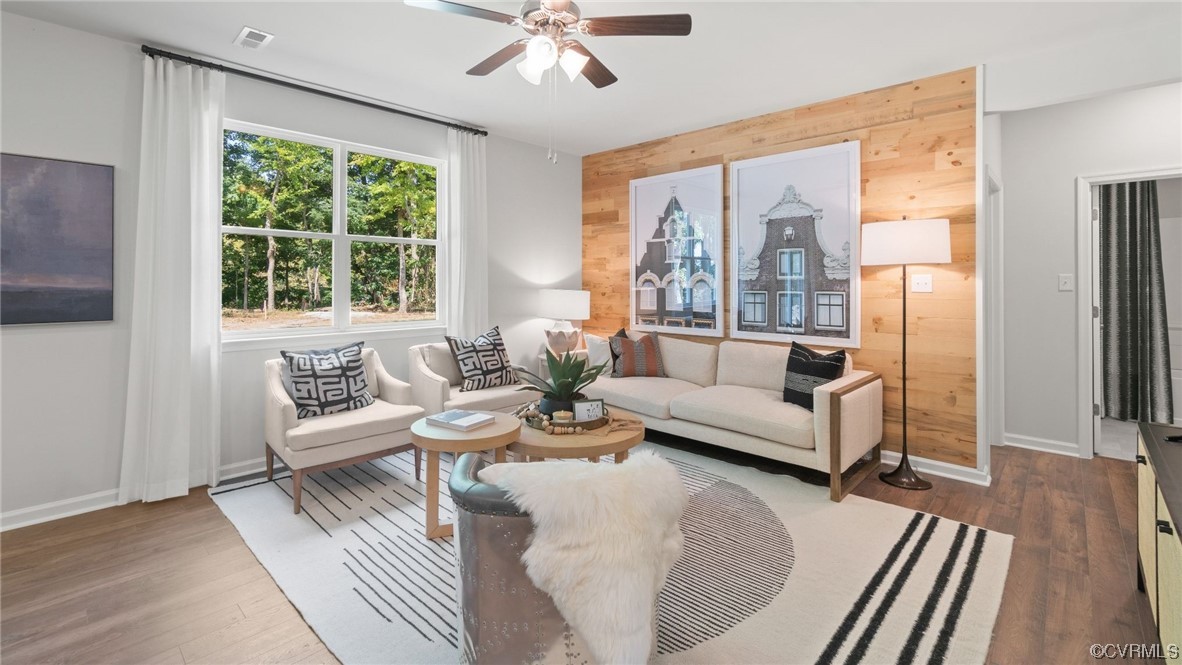 Living room featuring dark hardwood / wood-style floors, wood walls, and ceiling fan