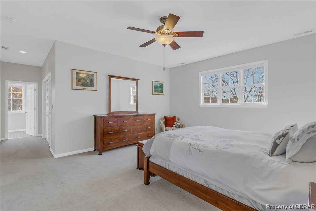 Bedroom featuring multiple windows, ceiling fan, and light carpet