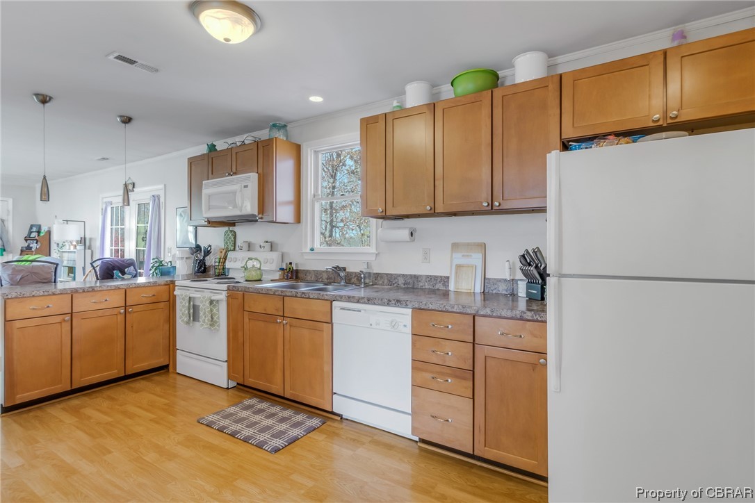 Kitchen featuring white appliances, light hardwood / wood-style floors, pendant lighting, and sink