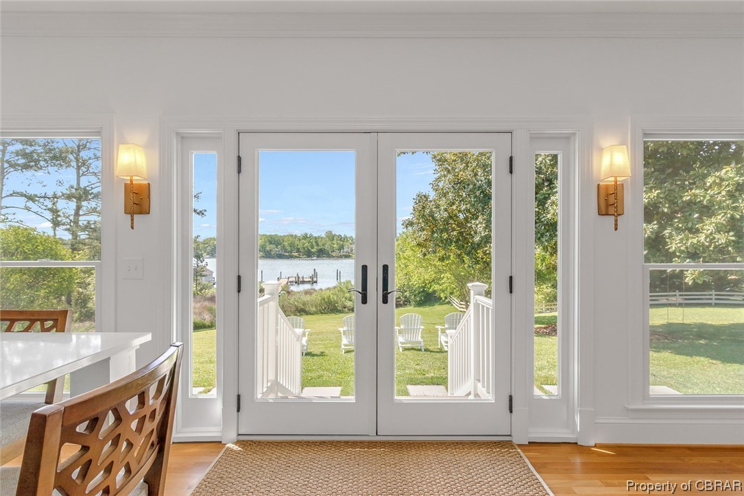 Doorway to outside featuring french doors, a water view, and light wood-type flooring