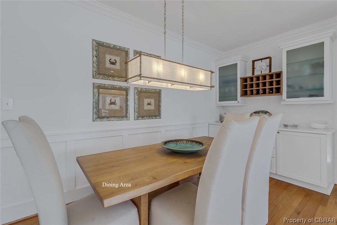 Dining space featuring light wood-type flooring, a notable chandelier, and crown molding