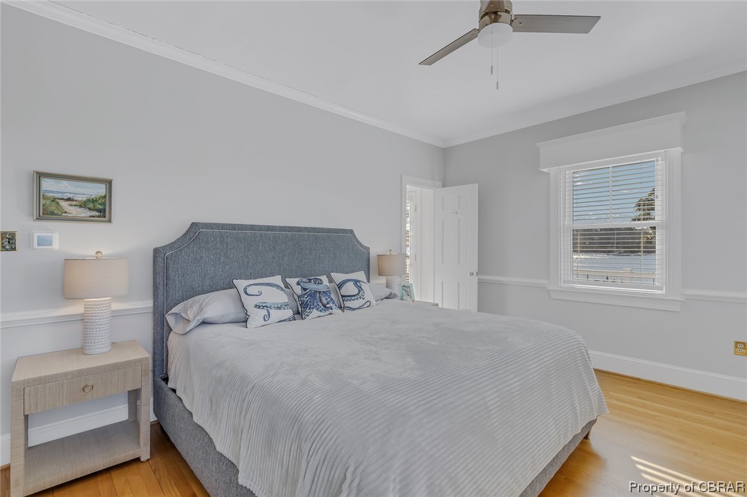Bedroom featuring light hardwood / wood-style floors, ceiling fan, and ornamental molding