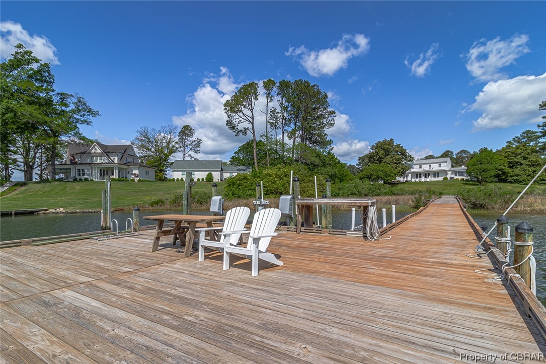 Deck with a yard, a water view, and a dock
