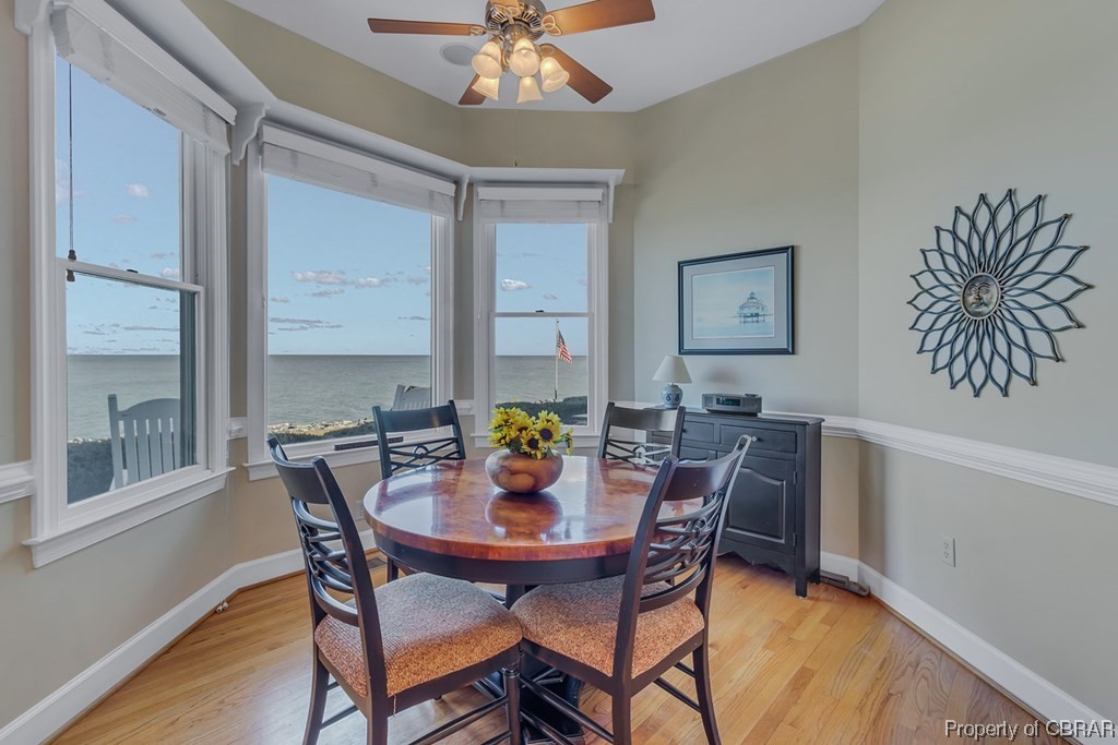 Dining room featuring light hardwood / wood-style flooring, a water view, and ceiling fan