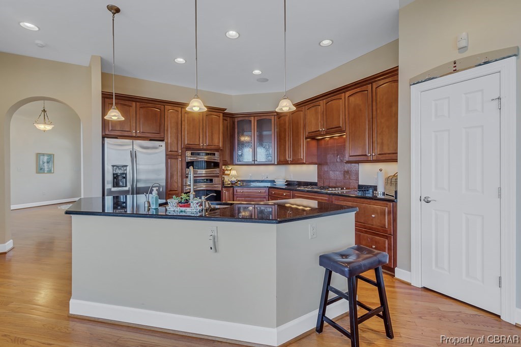 Kitchen featuring pendant lighting, appliances with stainless steel finishes, a breakfast bar, and light wood-type flooring