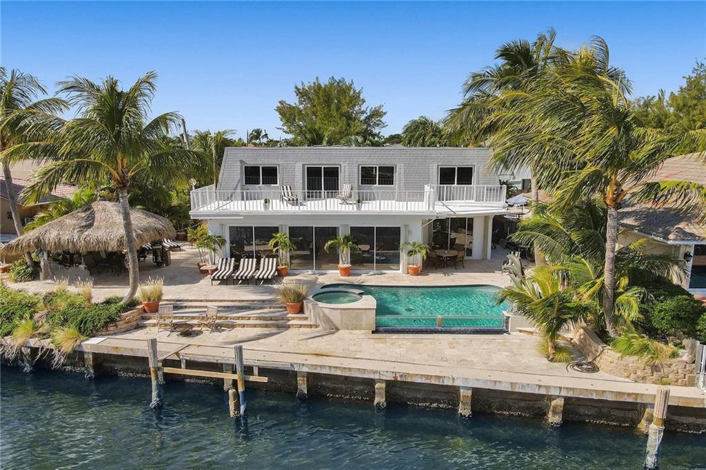 STUNNING INTRACOASTAL home in highly desirable Harbor Village! Updated with gorgeous chef's kitchen, 6 burner gas cooktop, subzero, formal dining, full wet bar, & library. Perfect for entertaining! High end marble floors, 2 big master suites with walk in closets and balconies. 2 Car Garage. Newer electric, plumbing, duct work, insulation. Infinity pool, spa, & tiki hut! Eastern exposure for constant breeze and shade in the afternoon. Perfect luxury vacation rental. Can easily convert to 7bd/5ba. No wake zone. No fixed bridges. 82' of Waterfront. Sits high in elevation. Approved plans for new dock and boat lift. Steps away from Harbor's Edge Park with fitness trail, dog park, playground, picnic areas, and beach! Walk to main beach with the best new restaurants on the sand! A MUST SEE!