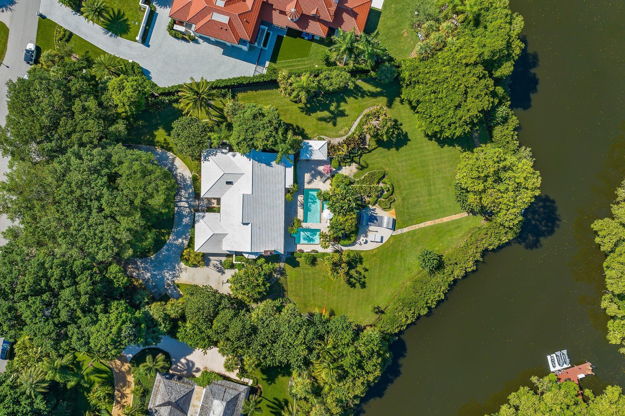 Rare 1.5 acres gem nestled in gated Seminole Landing.  Beautiful Banyan trees on water with baot access.  This 4 bedroom, 3.5 bath home features a private dock, lush tropical landscaping, pool and spa.  Intracoastal/Ocean access, 25 min to airport, 25 min to Palm Beach.